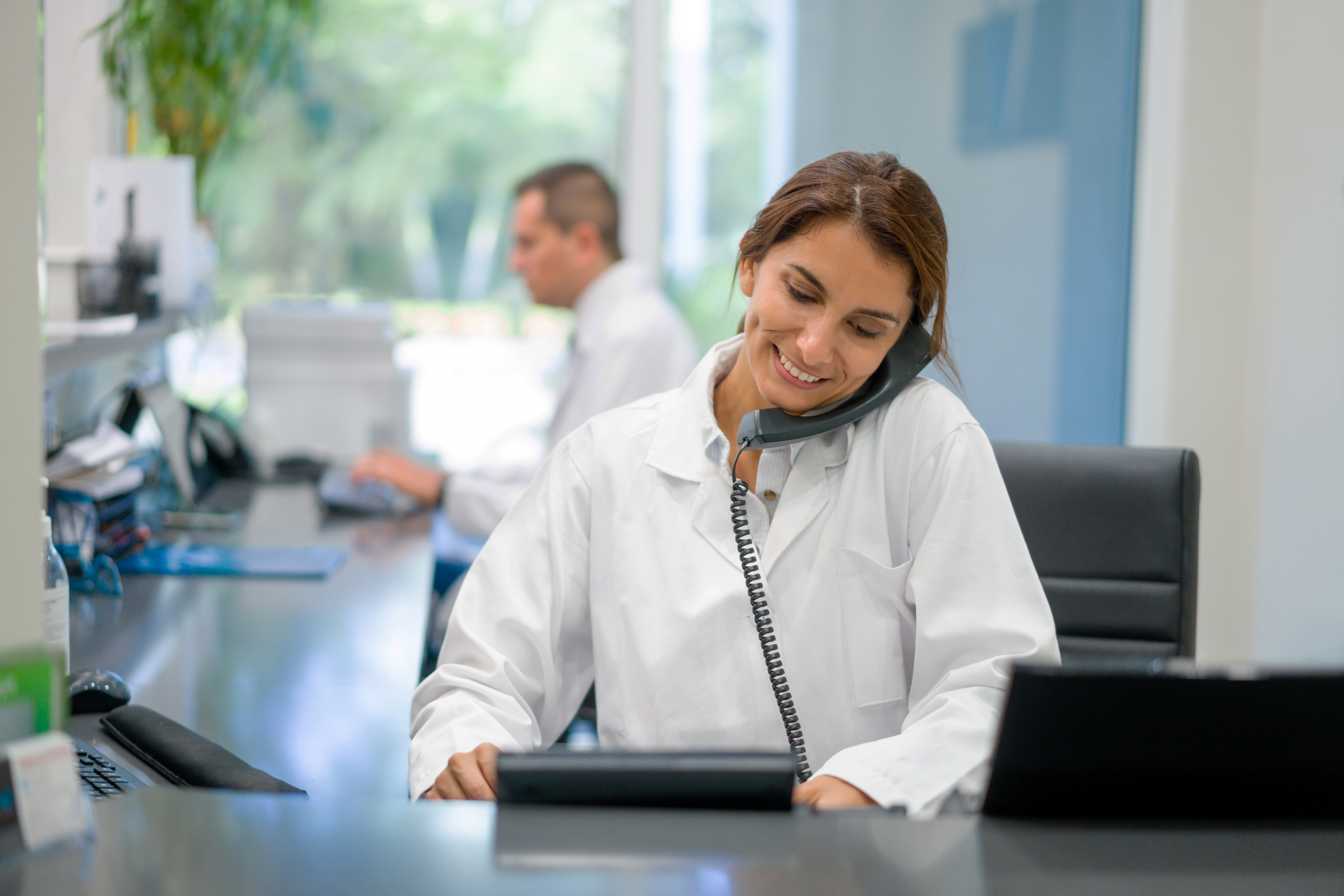 Latin American woman working as a receptionist at a doctor's office and talking on the phone -healthcare and medicine services concepts