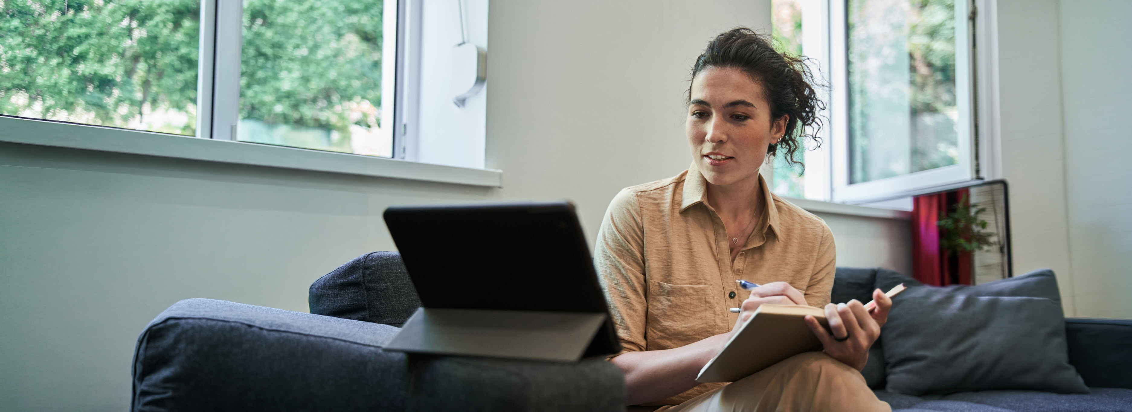 Its fine. Waist up portrait view of the brunette female psychologist making notes with pleasure smile while holding video call with patient