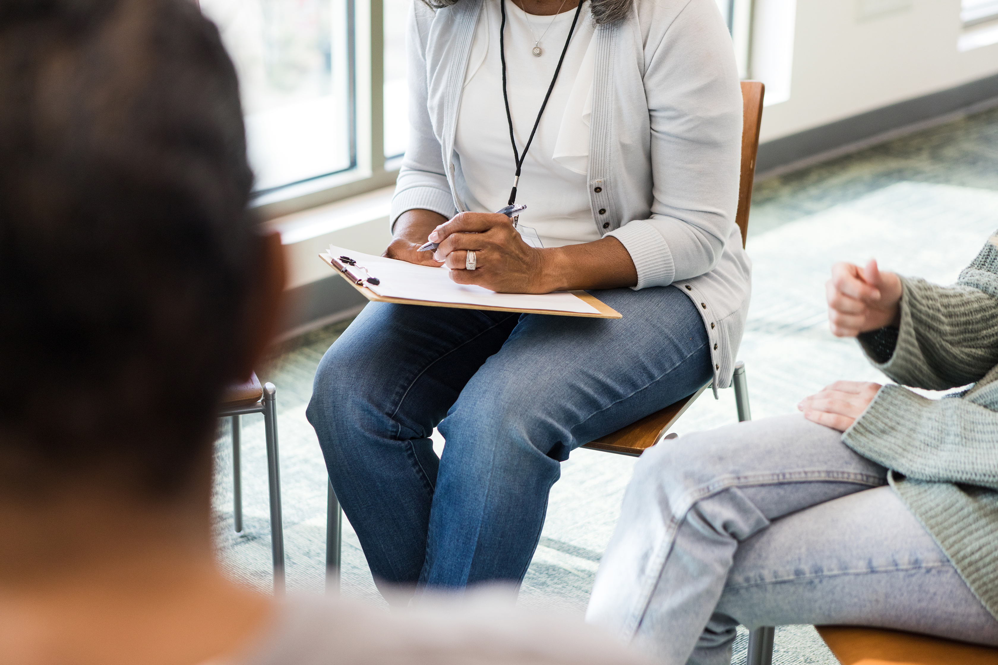 The unrecognizeable therapist takes notes during the meeting while listening to her clients talk.