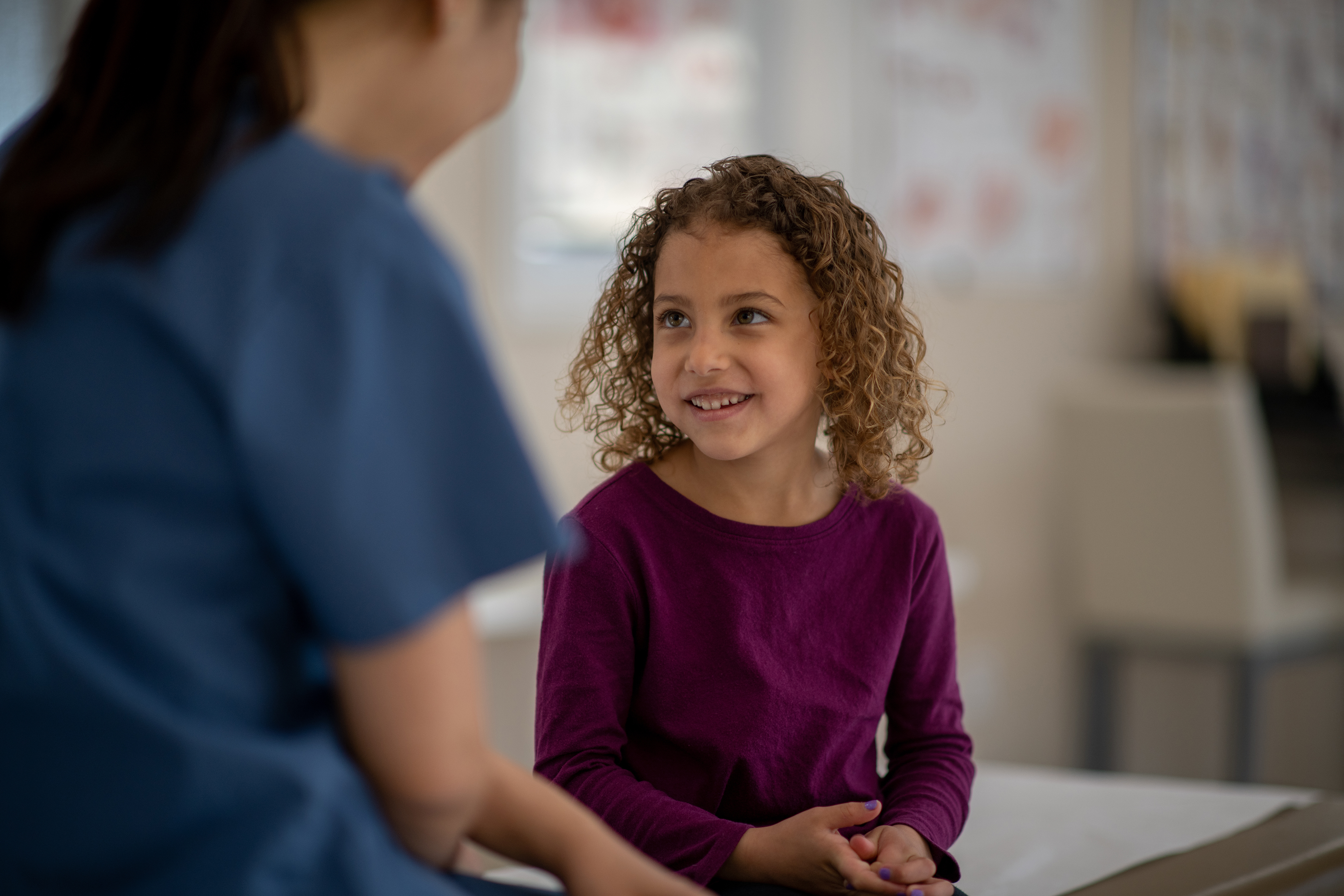 A friendly doctor performs a medical examination on a smiling young girl in a warm and inviting healthcare environment, symbolizing trust and professional care in pediatrics.