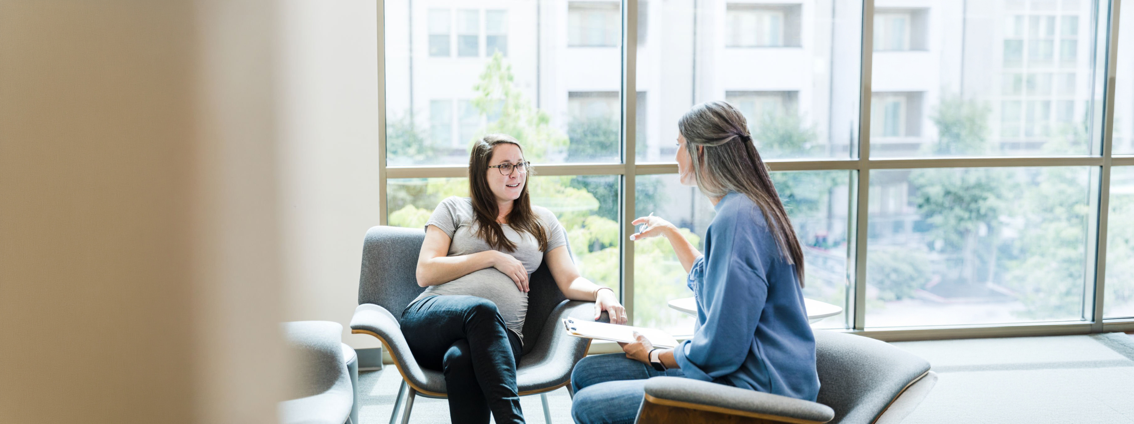 The young adult woman listens as the mature adult female therapist gives her advice for her pregnancy.