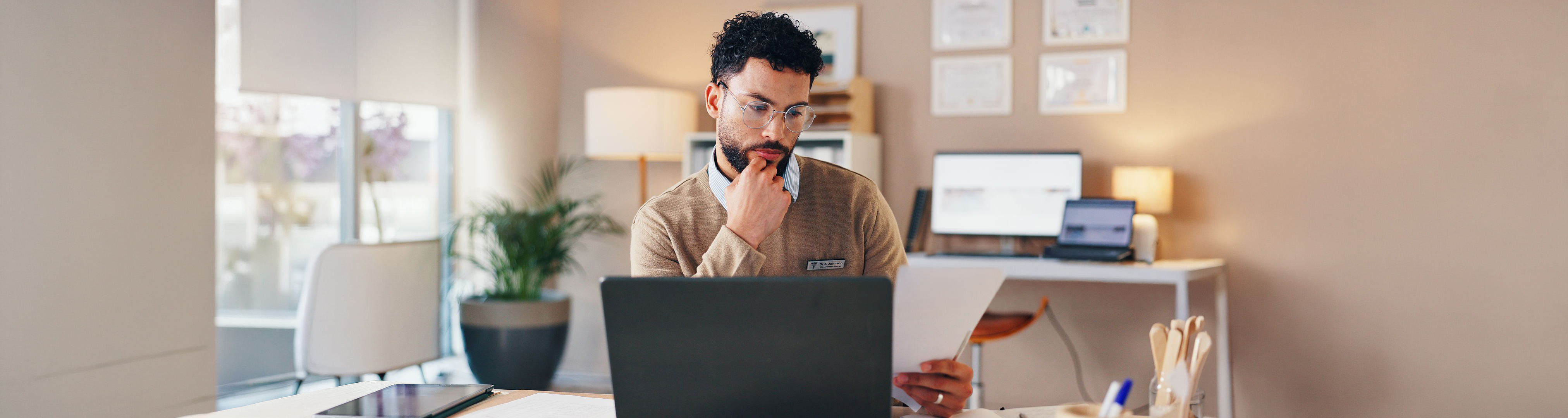 Doctor, man and laptop with documents in clinic for checking patient information and medical records. Healthcare, professional and paperwork for test results, health treatment planning and insurance